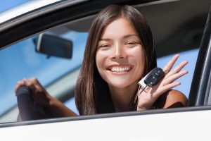 Teen sitting in drivers seat of a car holding keys.